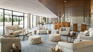 Een ruime, moderne lounge met diverse zitplaatsen, zoals banken en poefs, rond een centrale salontafel.