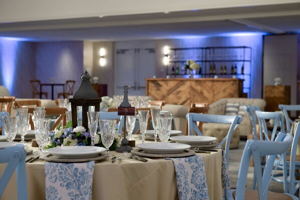 Un espace repas avec des tables dressées pour le service, agrémenté de beaux verres et de compositions florales.