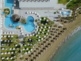 An aerial view of a resort with multiple swimming pools, sun loungers, and a beach area.