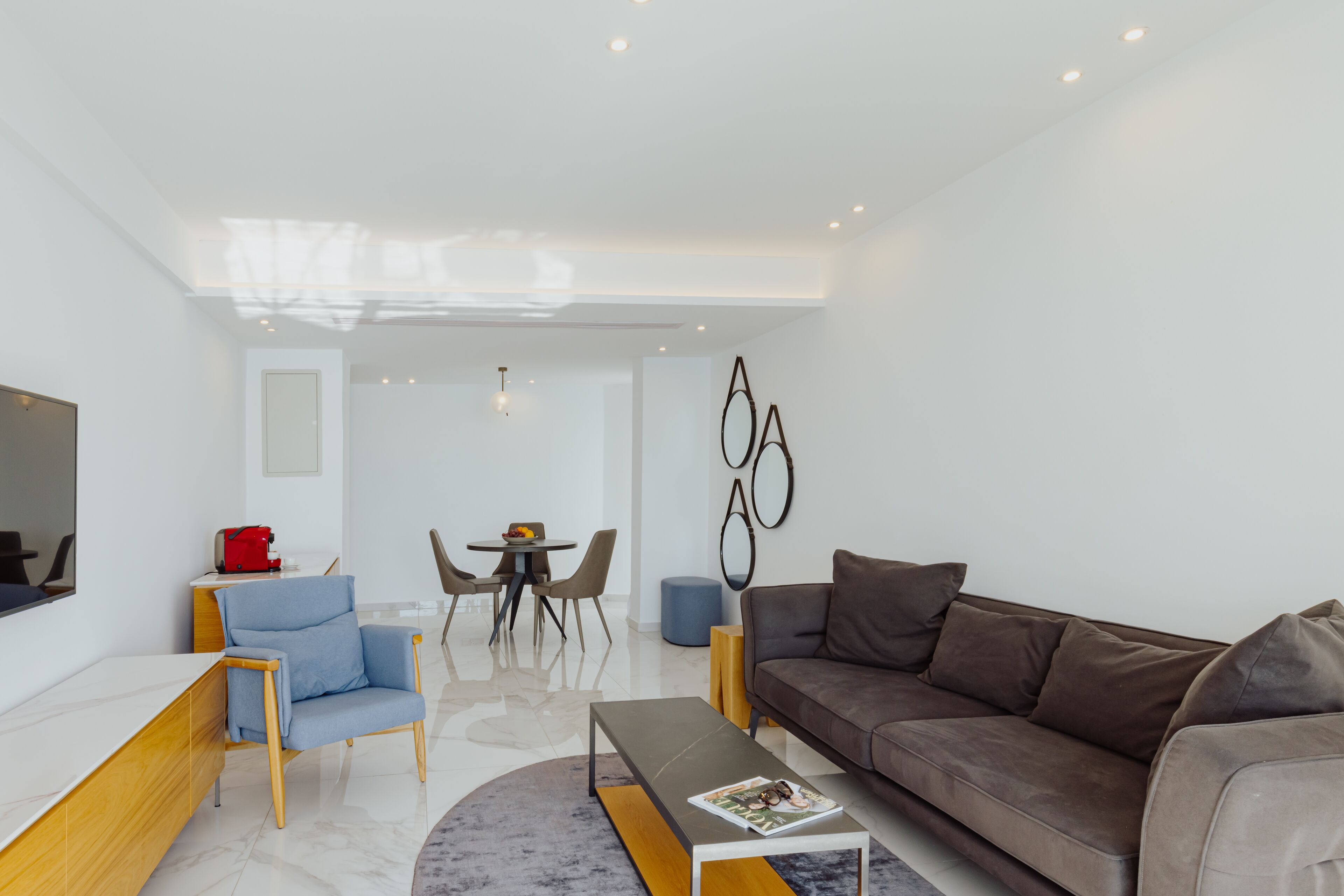 Ein modernes Wohnzimmer mit Sofa, Couchtisch, Fernseher und einem Essbereich mit Stühlen und Tisch.