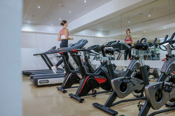 Un gimnasio con varias bicicletas estáticas y una cinta de correr.