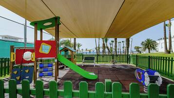 A playground with a slide, climbing area, and a shaded seating area.