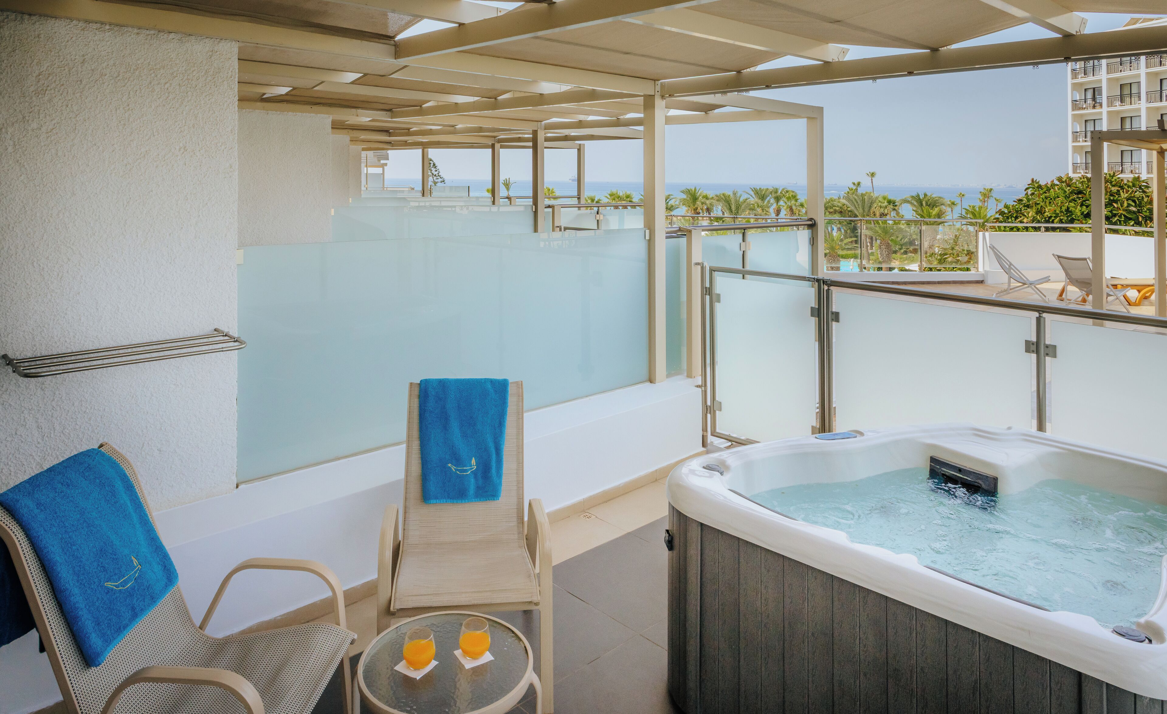 Un balcon doté d’un jacuzzi, de chaises longues et d’une paroi en verre.