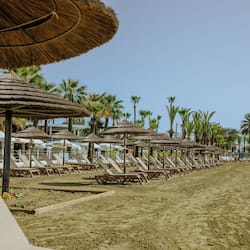 Na praia, espreguiçadeiras, guarda-sóis, toalhas de praia