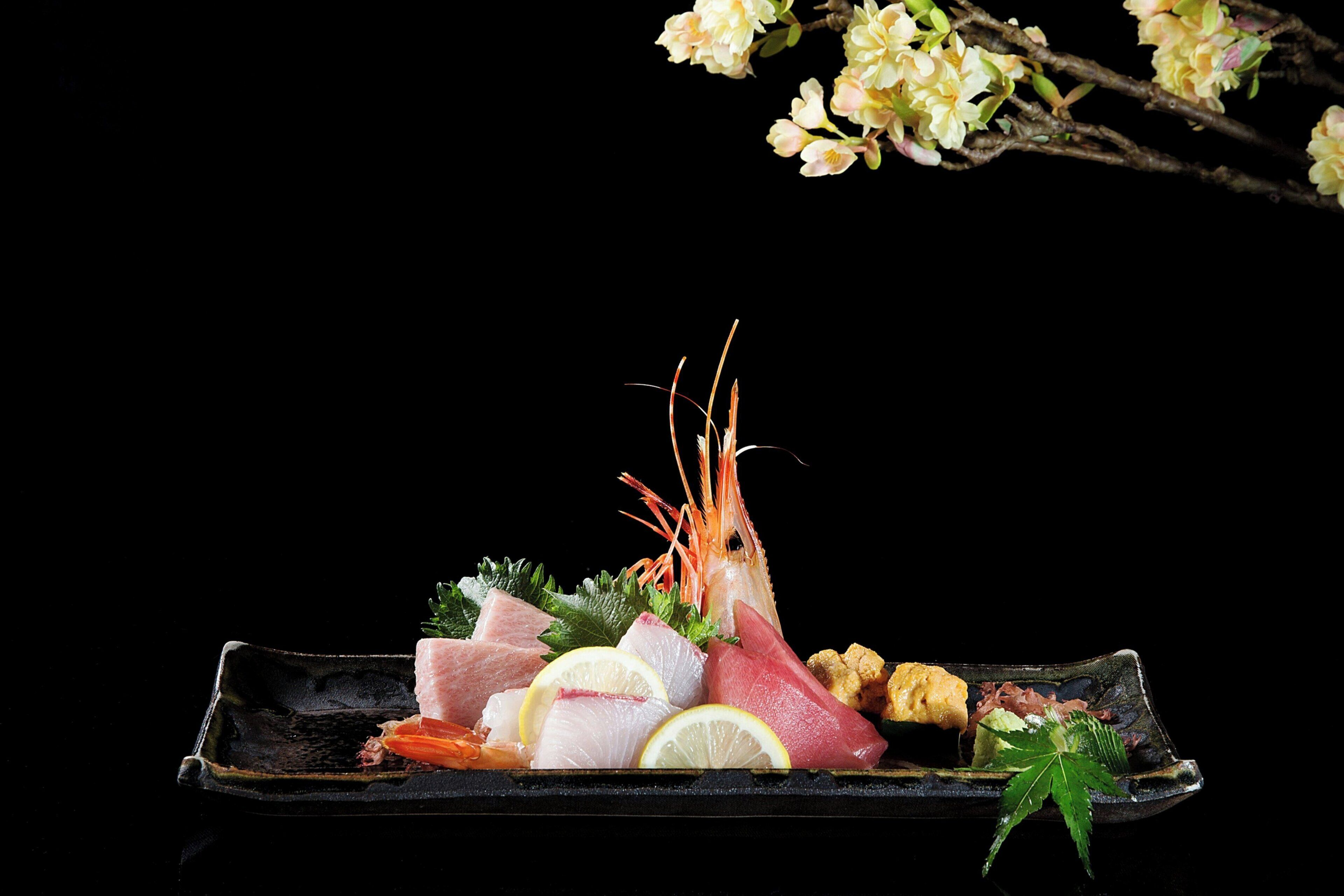 Un piatto nero con diversi frutti di mare e guarnizioni.
