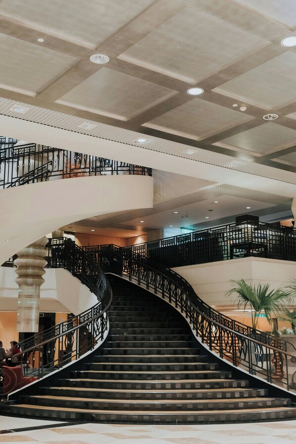 Una imponente escalera con barandales decorados que sube a un piso superior.