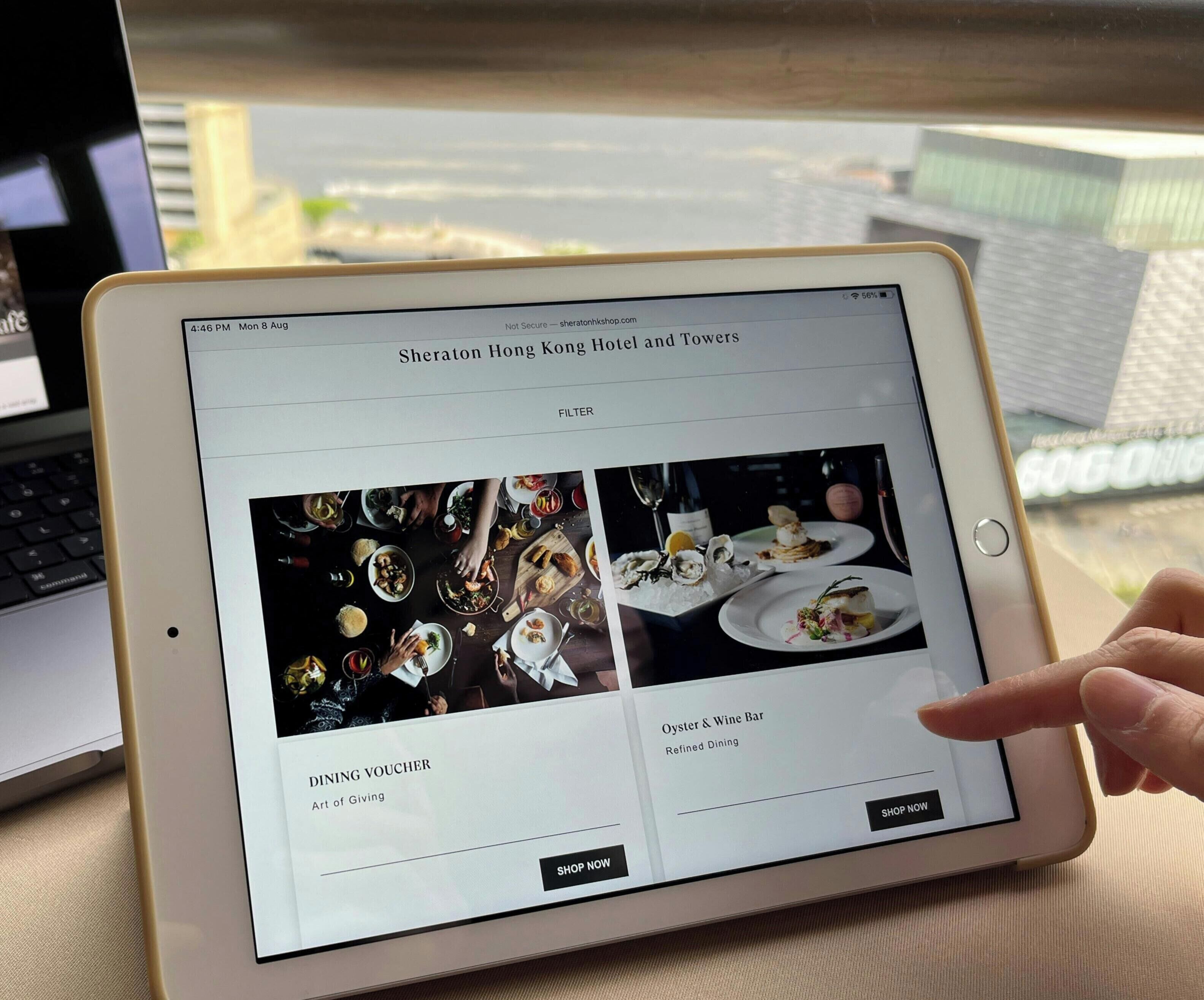 A tablet displaying a hotel website with dining options and a voucher offer.