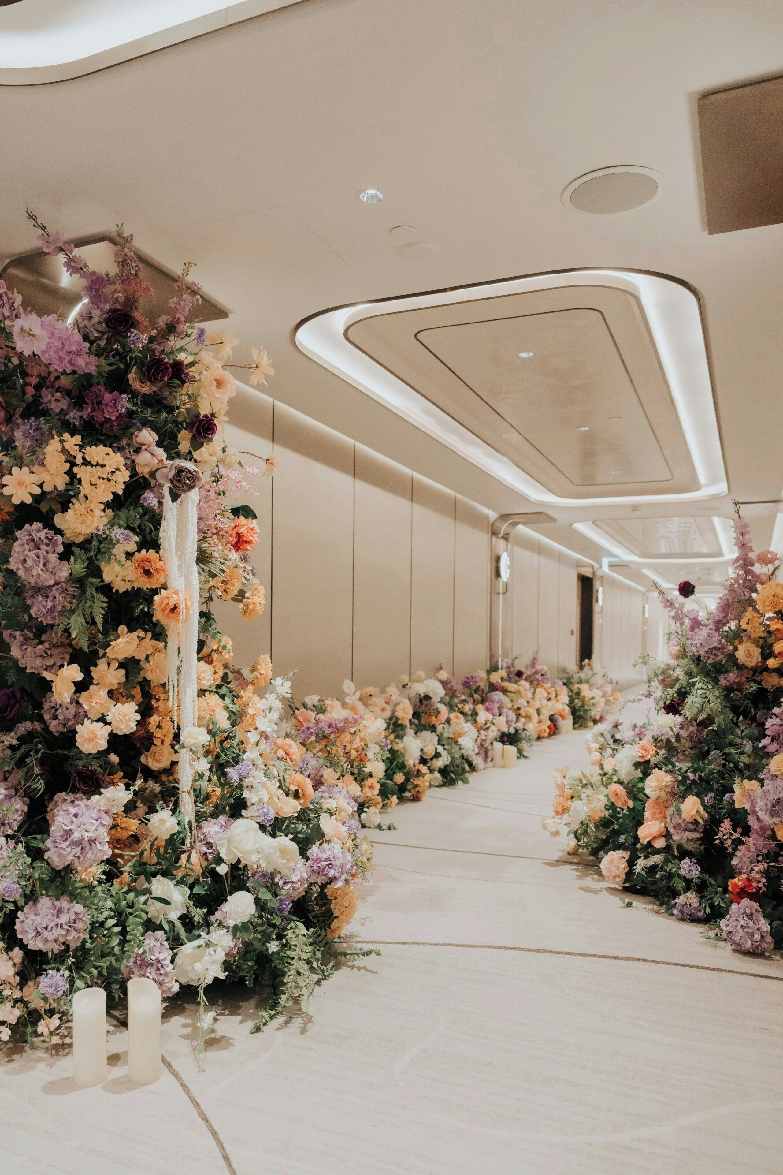 A corridor with floral arrangements and a modern ceiling design.