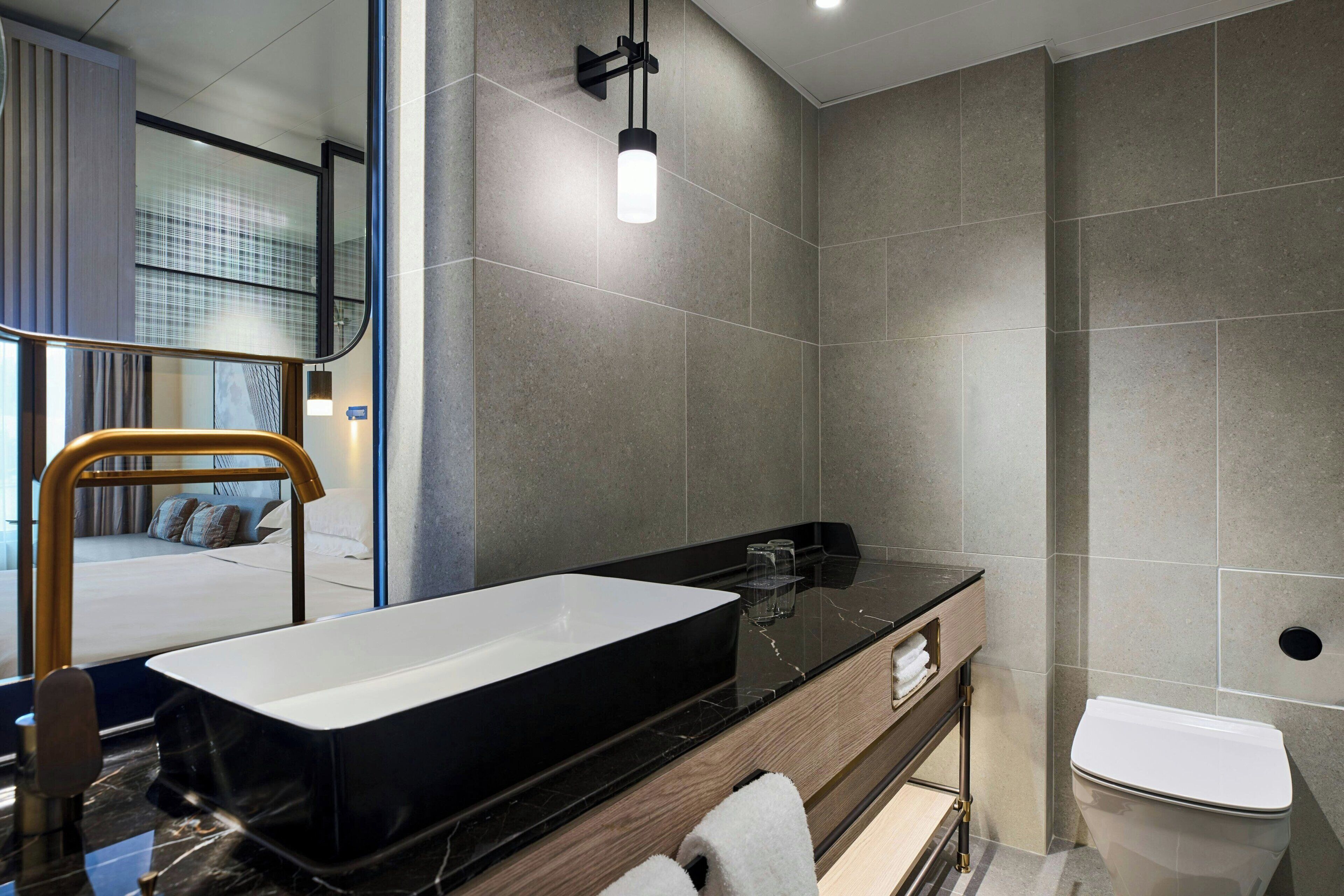 A modern bathroom with a large rectangular sink, a toilet, and a mirror.