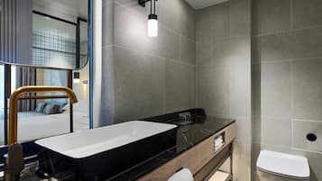 A modern bathroom with a large rectangular sink, a toilet, and a mirror.