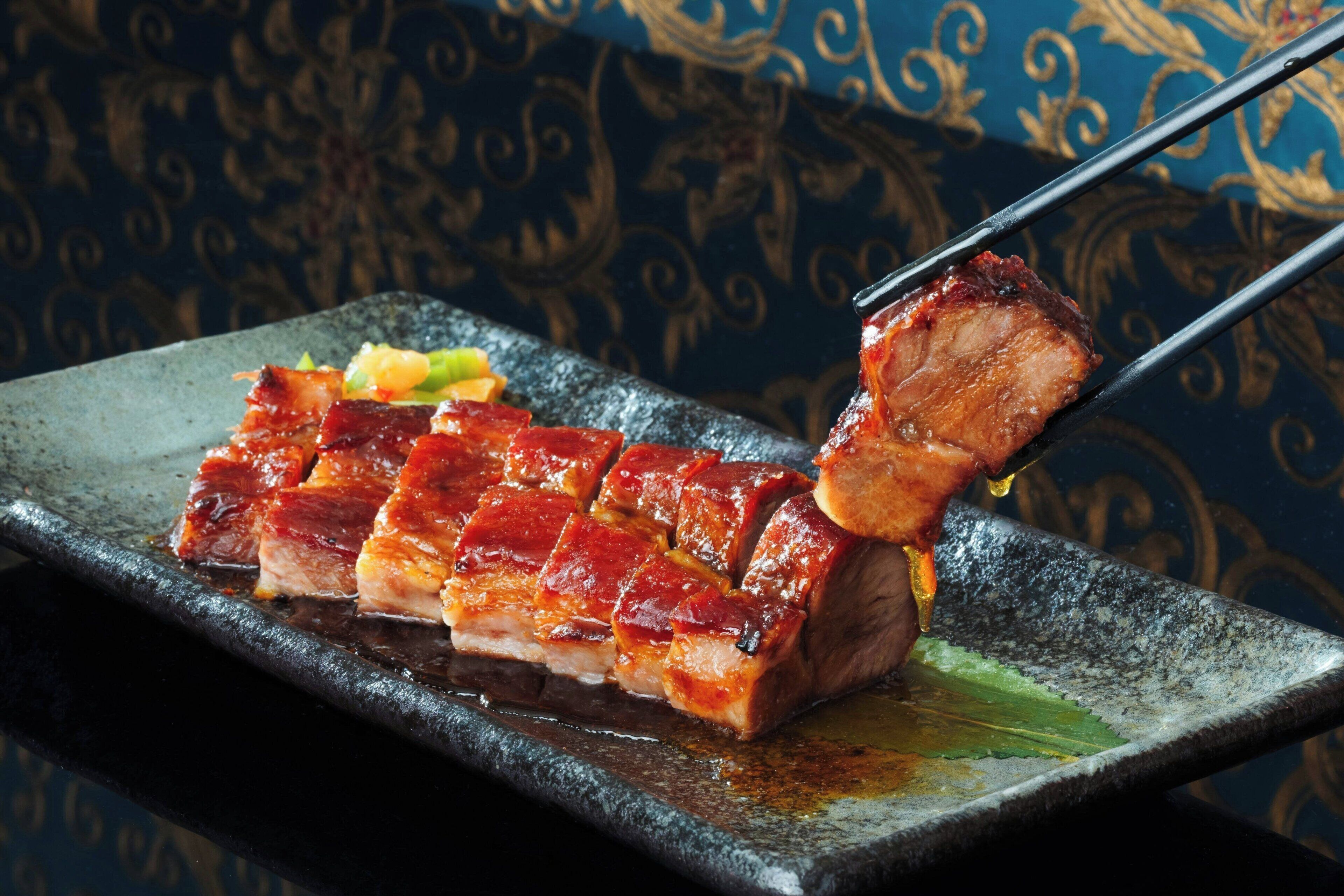 A plate with sliced meat and vegetables, a chopstick holding a piece of meat, and a decorative background.