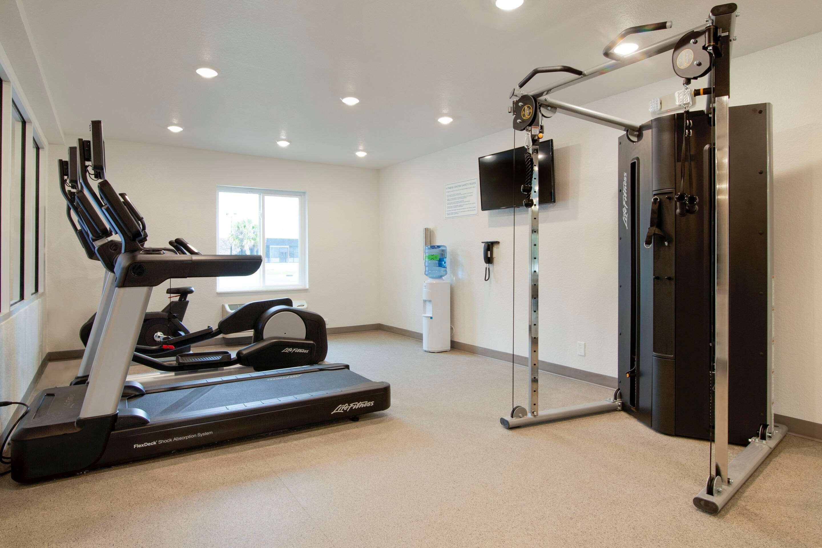 Un gimnasio equipado con cinta de correr, banco de pesas y barra de dominadas.