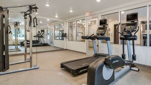 A gym with treadmills, a weight machine, and a mirror wall.