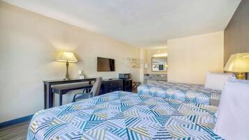 A hotel room with two beds, a desk with a chair, a desk lamp, a flat-screen TV, a mirror, and a wardrobe.