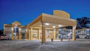 A hotel with a covered entrance, multiple balconies, and American flags. - Motel 6 Effingham, IL (Effingham)
