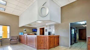 A reception area with a wooden counter, a television, and a clock on the wall. - Motel 6 Effingham, IL (Effingham)