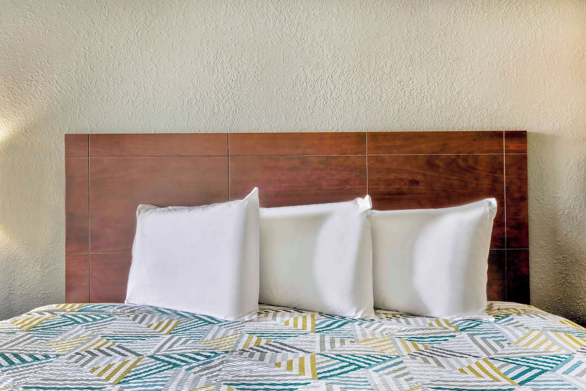 A bed with a patterned bedspread and a wooden headboard.