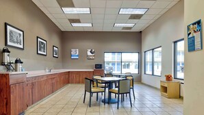 A spacious kitchen with a long counter, a dining area with chairs, and large windows providing natural light. - Motel 6 Effingham, IL (Effingham)