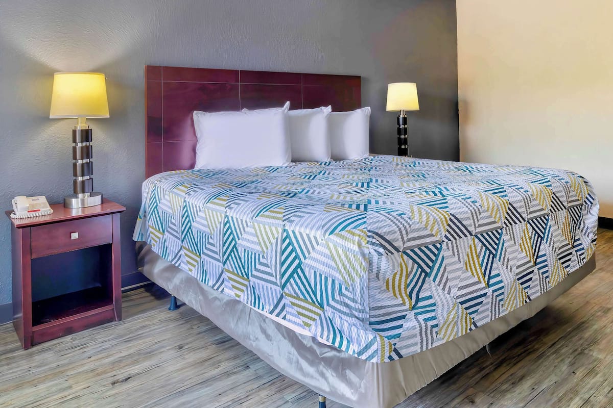 A hotel room with a large bed, two bedside tables, and a headboard.