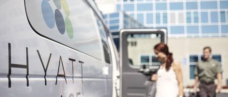 A white van with "HYATT PLACE" written on it, parked in front of a building with a blue and white facade.