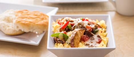 A breakfast dish with eggs, vegetables, and cheese on a white plate.