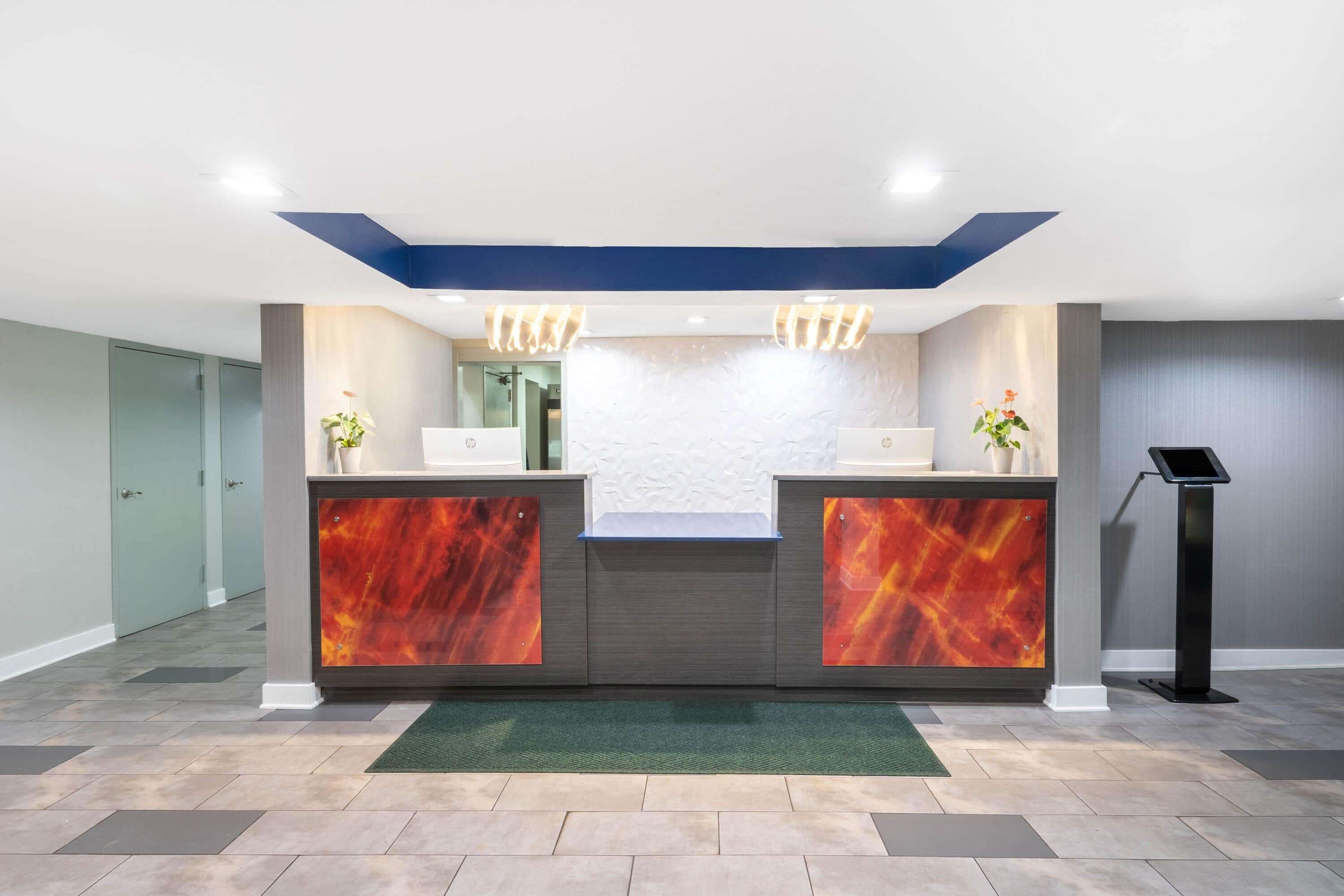 A reception area with a marble reception desk, a digital information kiosk, and a green carpet.