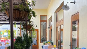 Un espace extérieur aménagé pour les repas, avec des tables, des chaises, des plantes en pot et un chemin.