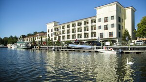 A waterfront hotel with multiple balconies, a dock, and a boat. - Delamar Greenwich Harbor (Greenwich)