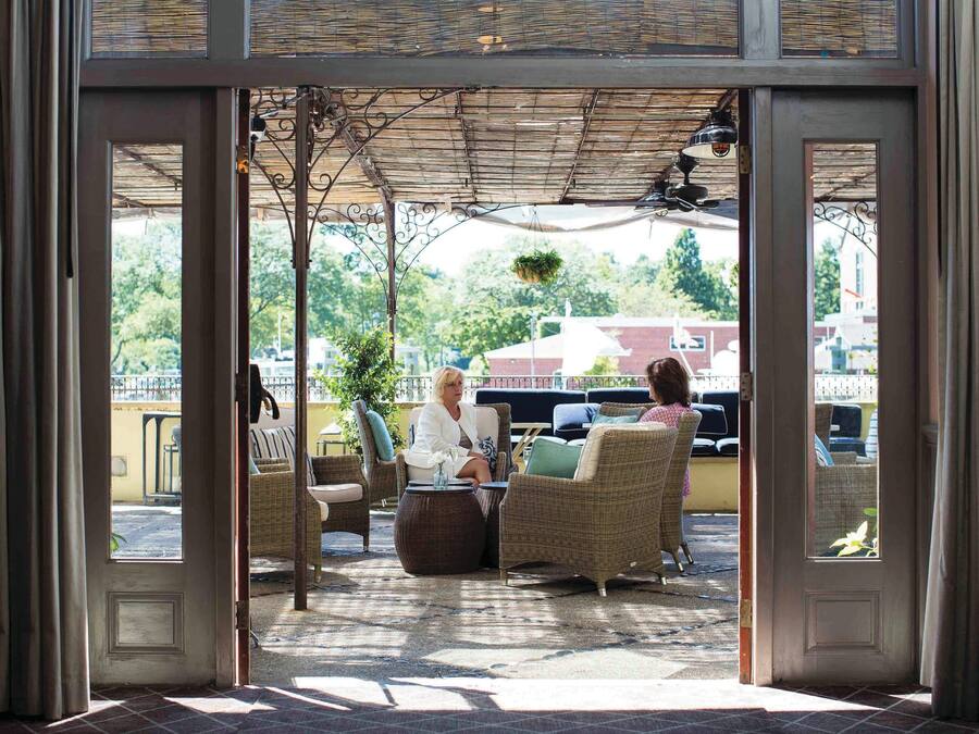 Een terras met rieten meubilair en een overkapte pergola.