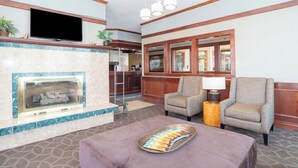 A lobby with a fireplace, seating area, and a television mounted on the wall.