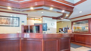 A reception area with a wooden reception desk, a clock on the wall, and a framed picture.