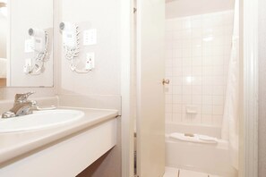 A bathroom with a sink, mirror, hair dryer, and shower. - Sandman Hotel Terrace (Terrace)