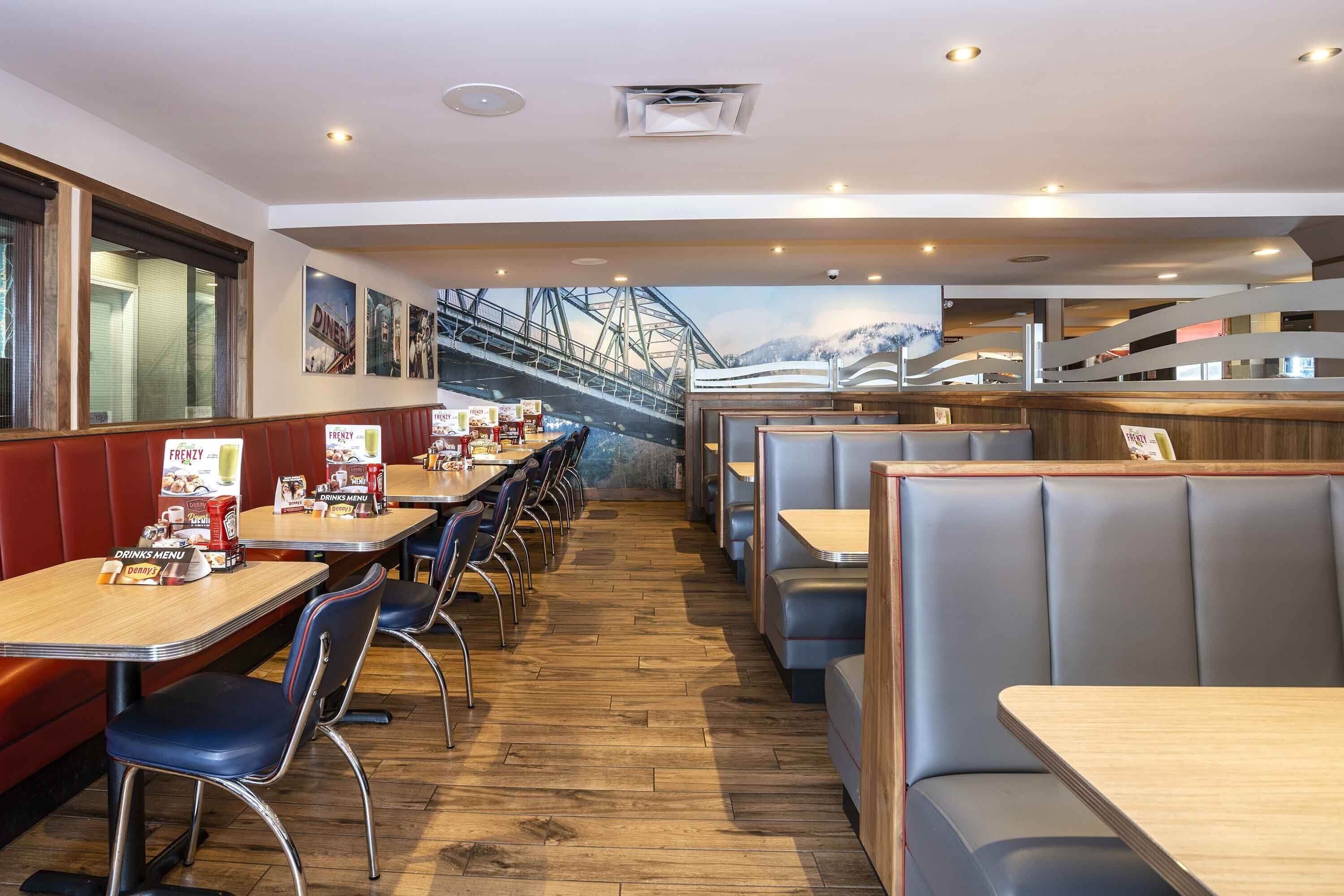 Un ristorante con cabine e tavoli, pavimento in legno e un murale raffigurante un ponte.