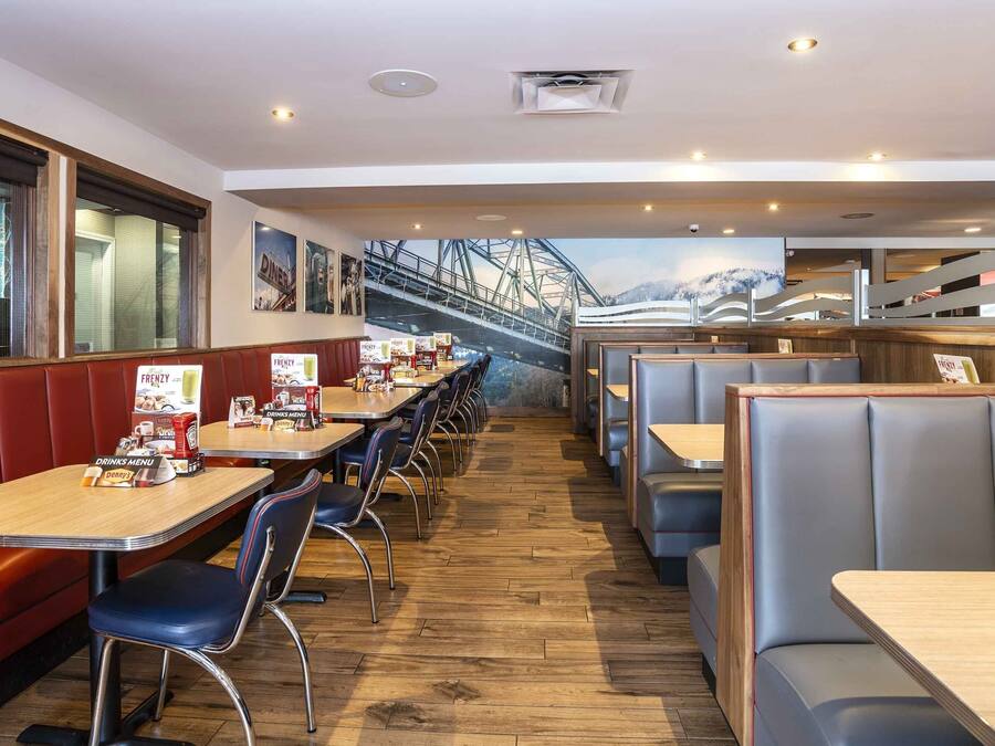 Un ristorante con cabine e tavoli, pavimento in legno e un murale raffigurante un ponte.