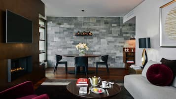 A modern living room with a fireplace, a round dining table, and a sofa with a red cushion.