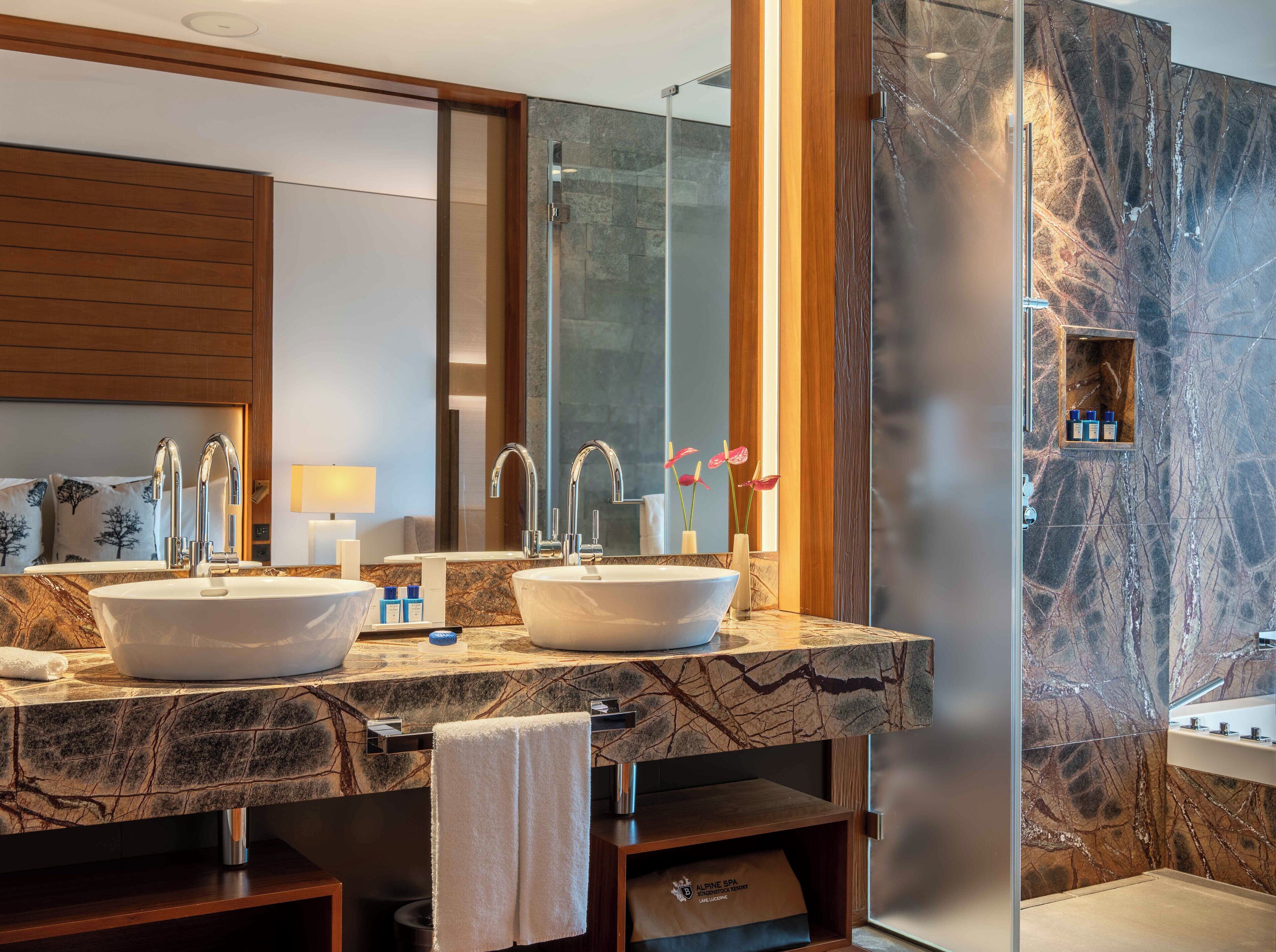 A modern bathroom with two sinks, a large mirror, and a glass shower enclosure.