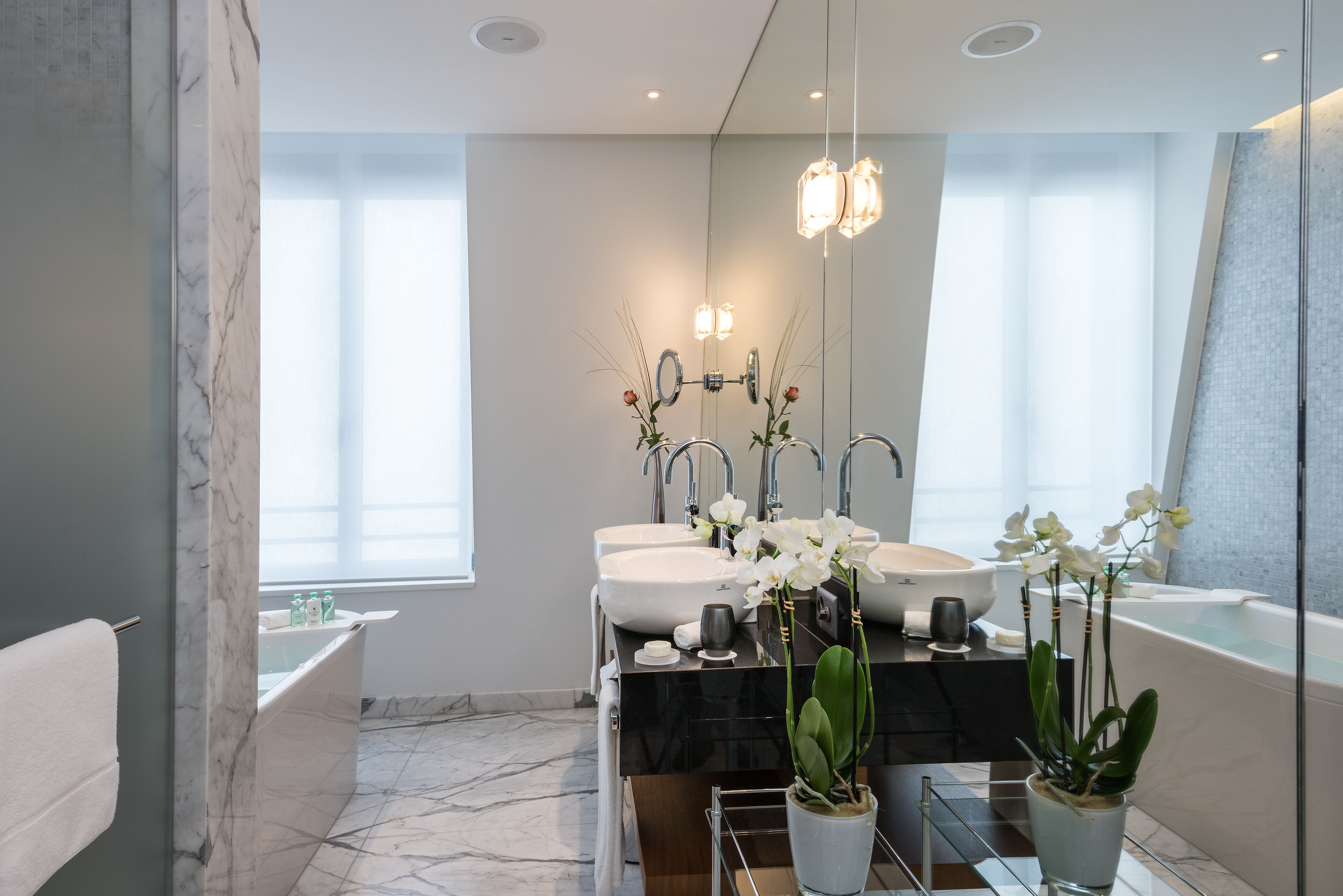 Un baño moderno con dos lavamanos, una bañera y un espejo grande.