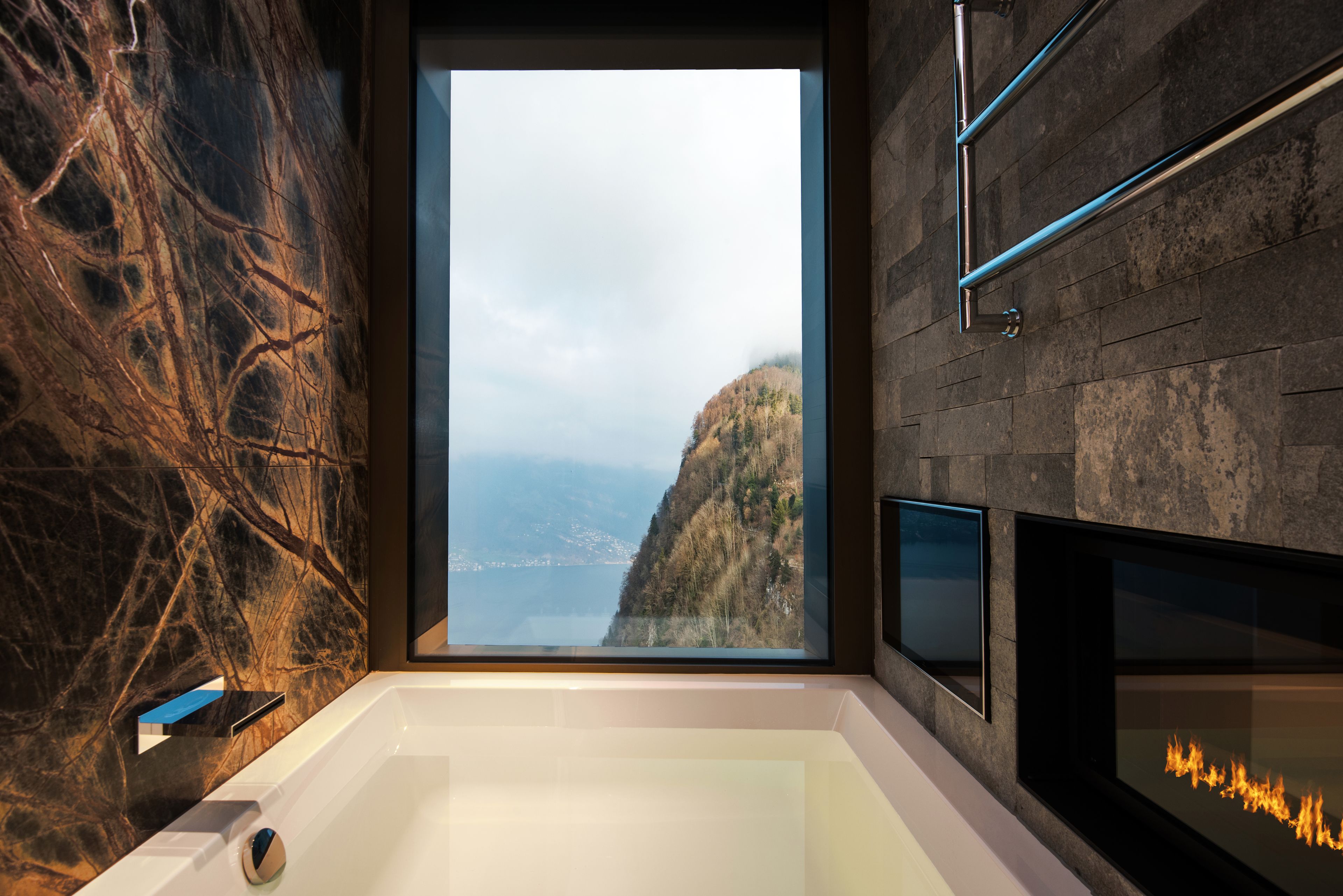 Une salle de bain moderne avec une grande baignoire, une vue sur un paysage montagneux et une cheminée.