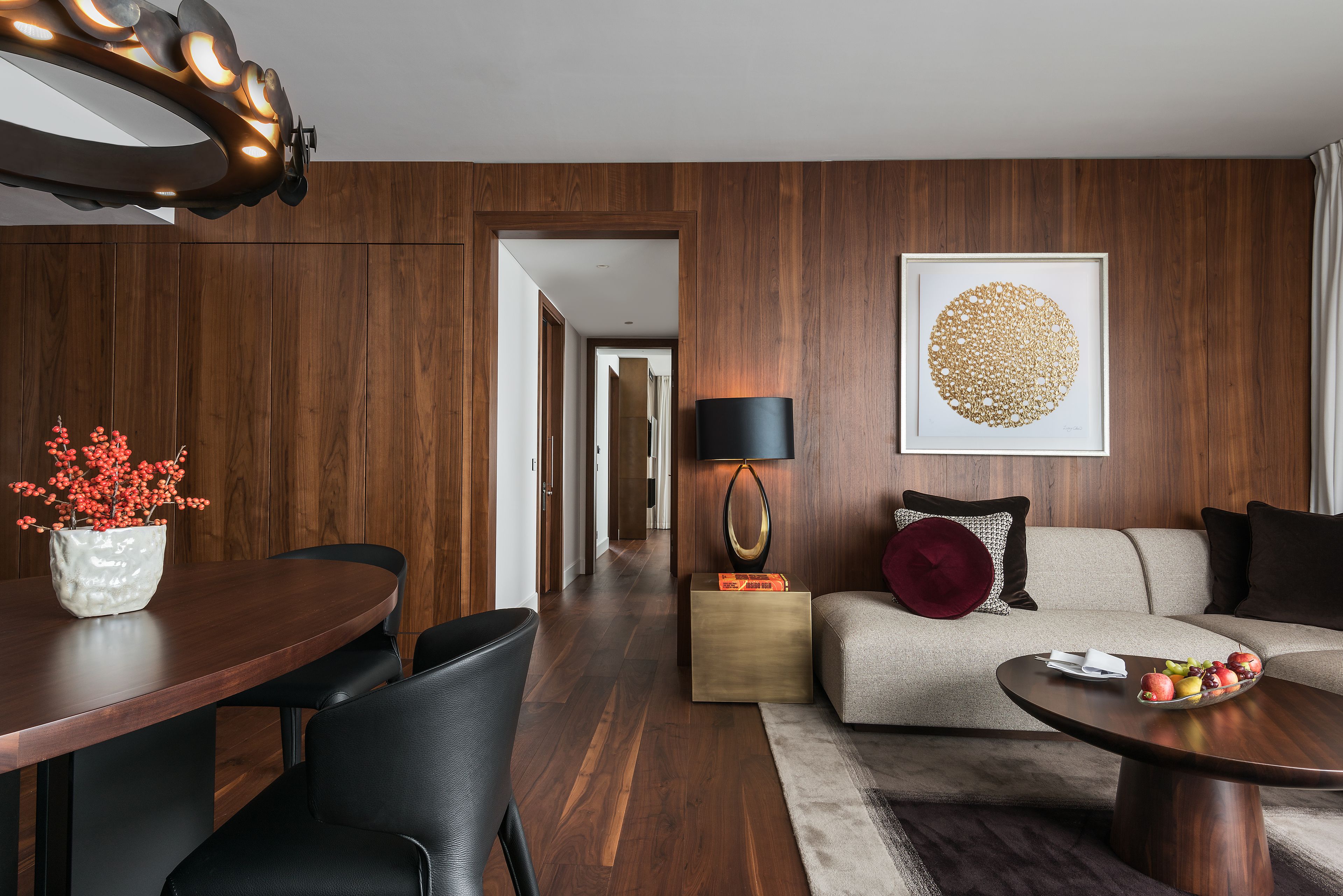 Una sala de estar moderna con piso de madera, una mesa de comedor redonda, un sofá y una mesa de centro.