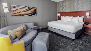 Habitació d'hotel moderna amb un llit gran, un sofà i una taula petita.