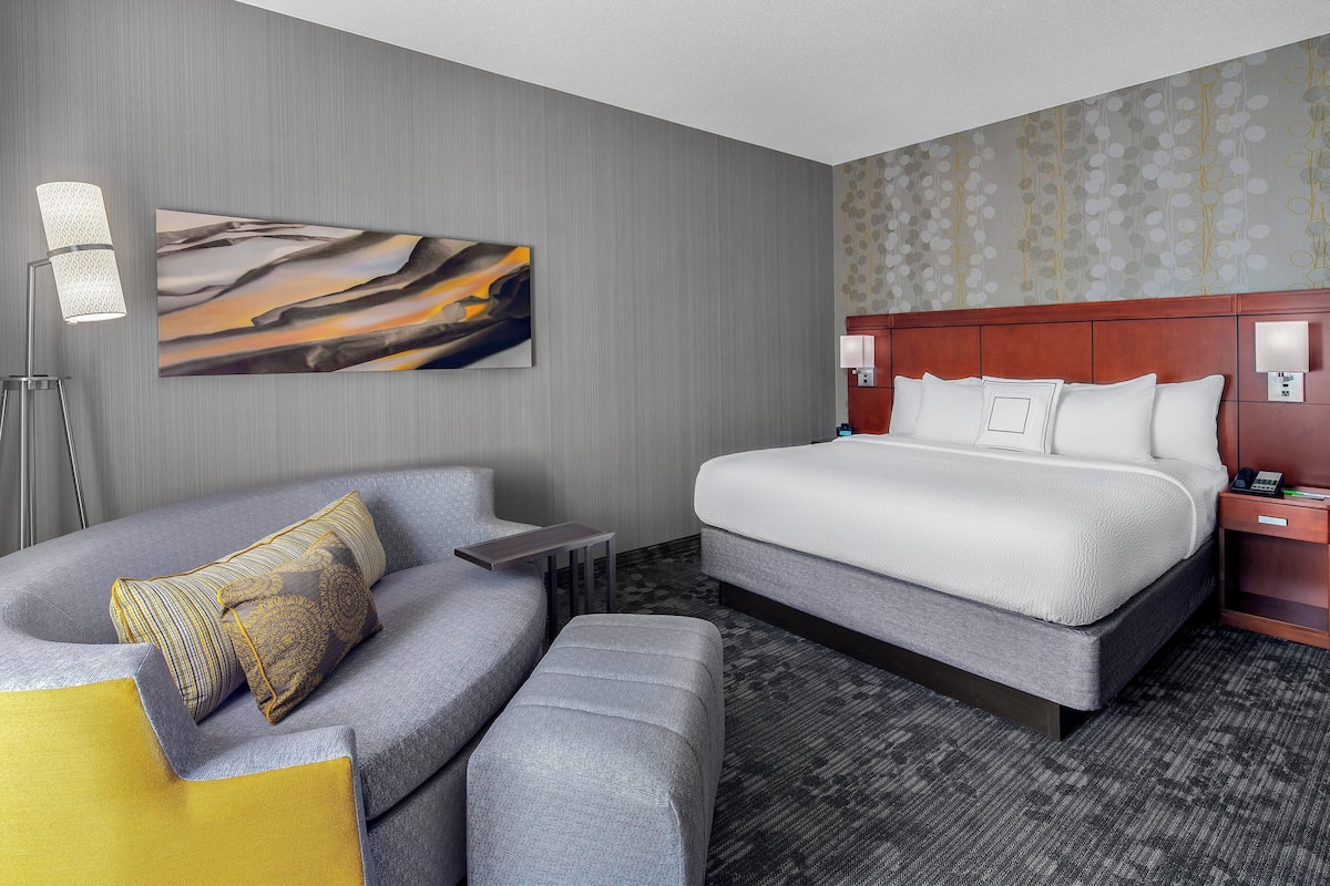 Ein modernes Hotelzimmer mit einem großen Bett, einer Couch und einem kleinen Tisch.