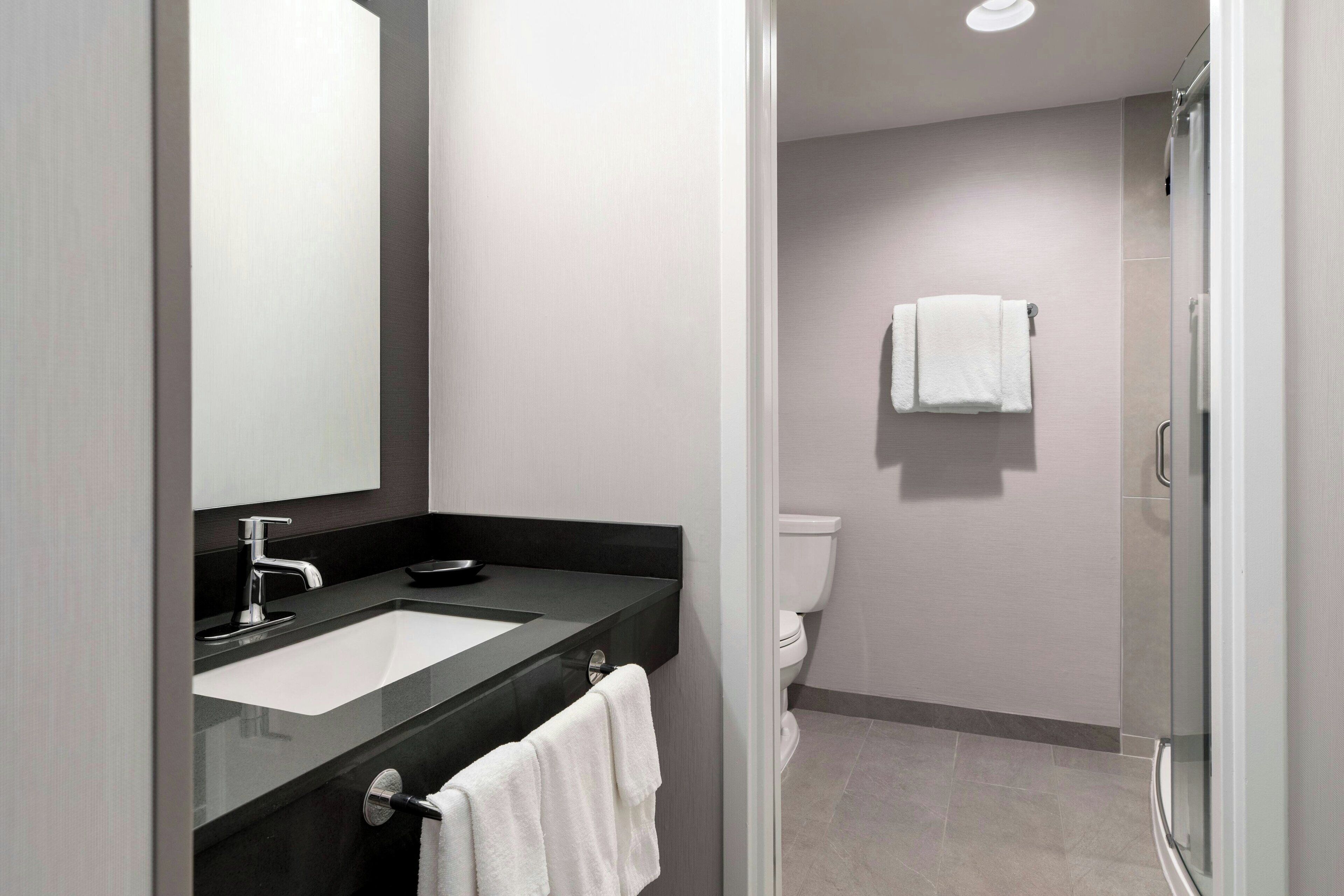 A modern bathroom with a sink, mirror, and toilet.
