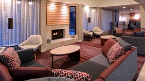 A modern lounge area with sofas, armchairs, a fireplace, and a view of the outdoors. - Sonesta Select Kansas City Airport Tiffany Springs (Kansas City)