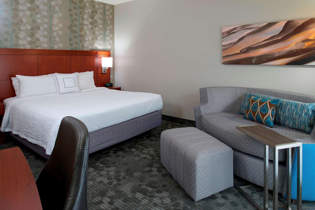 Une chambre d’hôtel avec un lit, un canapé, une petite table et une chaise.