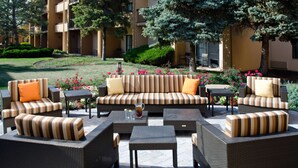 An outdoor seating area with wicker furniture, a sofa, and a coffee table. - Sonesta Select Kansas City Airport Tiffany Springs (Kansas City)