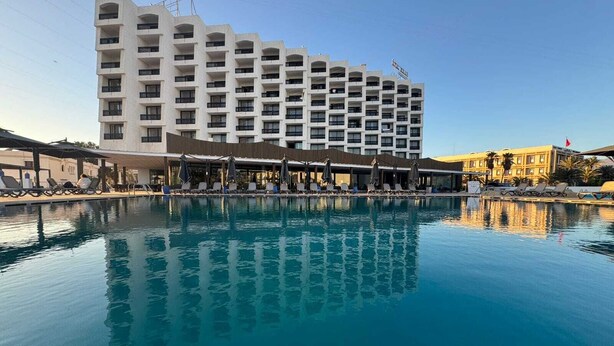 Un hotel con piscina, varios balcones y cielo despejado.