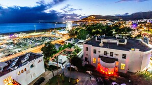 Un hotel frente al mar con estacionamiento, un edificio de spa y una noria al fondo.