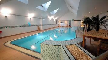 Ein Hallenbad mit gefliestem Boden, einer Holzbank und einem Stuhl.