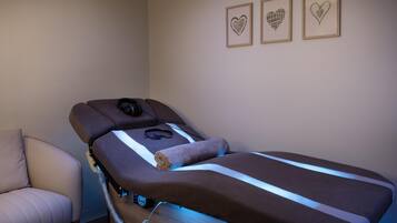 A massage therapy room with a massage table, headphones, and a control panel.