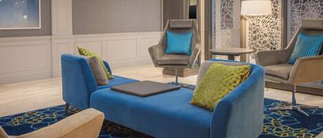 A modern lounge area with a blue sofa, two armchairs, and a small table.